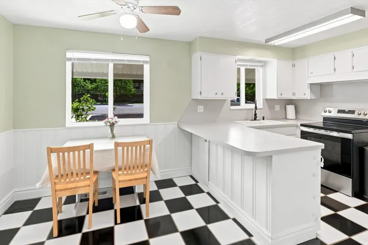 Kitchen featuring checkerboard flooring, white cabinetry, solid surface countertops, and stainless steel appliances