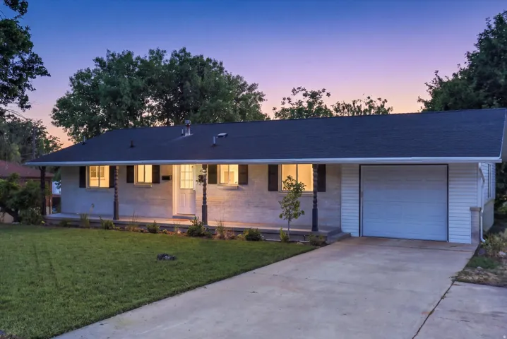 Single-story residence featuring a dark shingle roof and white brick façade
