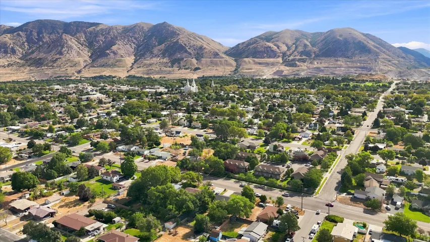Aerial perspective of a populated area with established residential structures and mature landscaping, set against a mountainous backdrop
