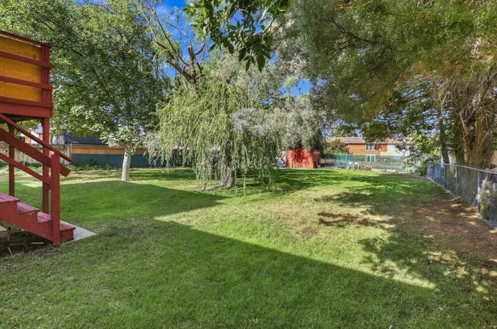 Expansive grounds featuring a manicured lawn, mature shade trees including a weeping willow, and red-finished outbuildings