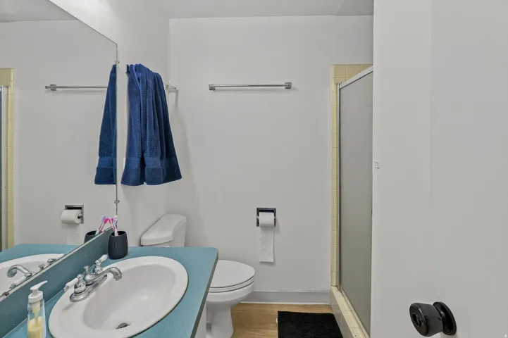 Bathroom featuring a vanity with an integrated sink, a toilet, and a shower enclosure
