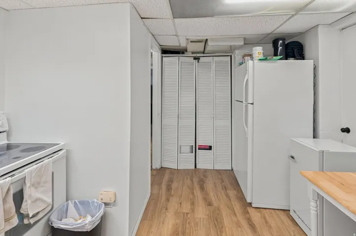 White appliances, wood-finish flooring, and white walls