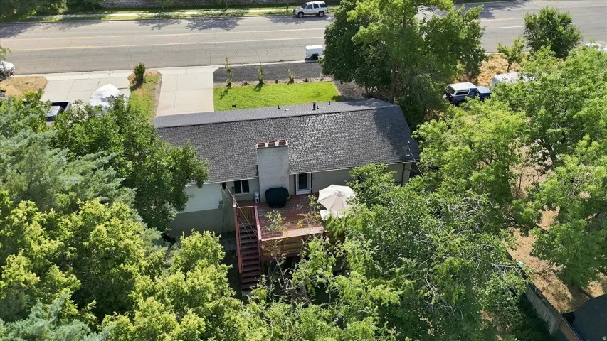 Rear exterior with a wood deck, chimney, and dark shingle roof