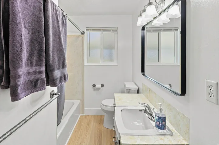Bathroom featuring a vanity with an integrated sink, a large wall mirror, and a full bathtub with shower
