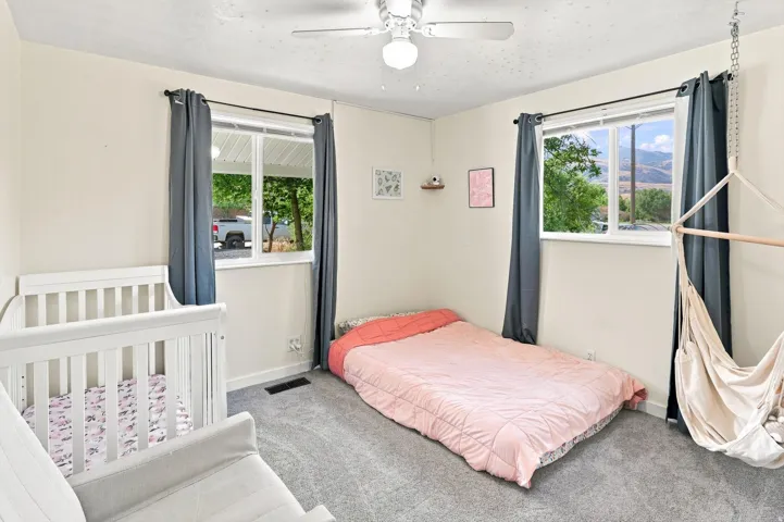 Neutral wall finishes, recessed windows, gray carpeting, and a ceiling fan with integrated lighting