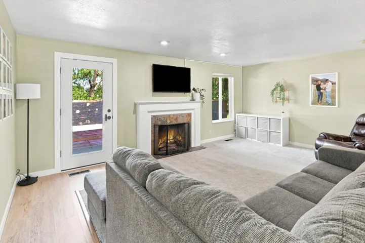 Living area featuring a floor-to-ceiling stone-faced fireplace with a white mantel, recessed lighting, and a glass-paneled exterior door