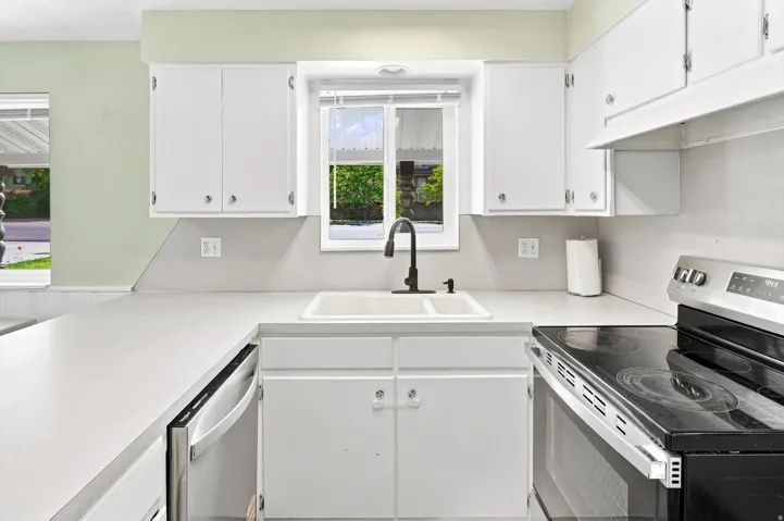 White cabinetry, white countertops, built-in dishwasher, stainless steel range, and a dual-basin sink with a matte black faucet