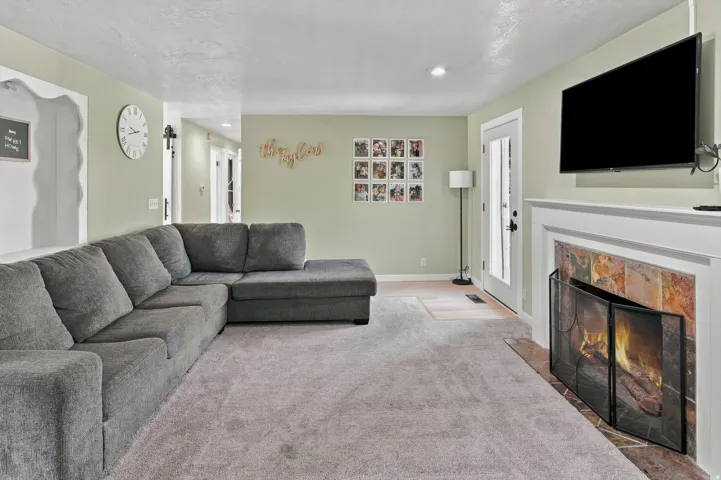 Carpeted living area with a tile-surround fireplace, classic white mantel, and a door with frosted glass panels