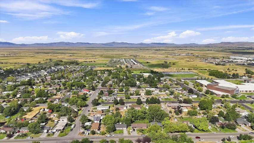 Residential neighborhood with mature trees, surrounded by expansive natural landscapes and distant mountains