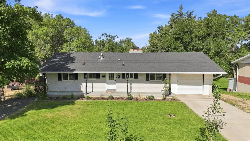 Single-story residence featuring a dark shingle roof, white exterior, attached garage, and a covered front porch with decorative columns