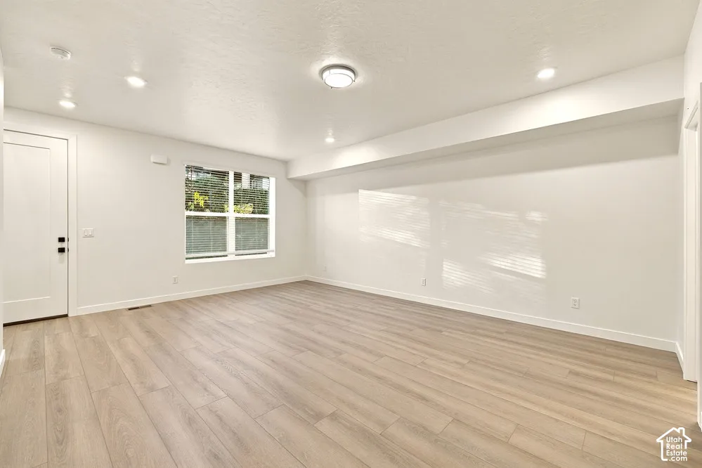 Interior space featuring wood-finish flooring, recessed lighting, a centered ceiling-mounted light fixture, and a large window with white trim