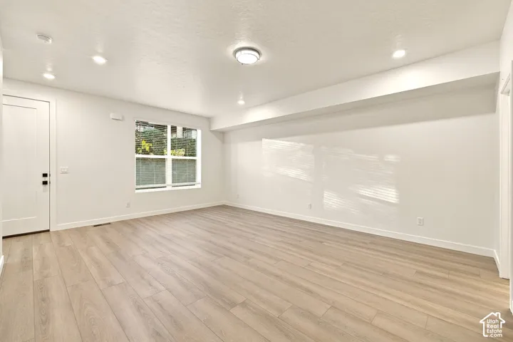 Interior space featuring wood-finish flooring, recessed lighting, a centered ceiling-mounted light fixture, and a large window with white trim