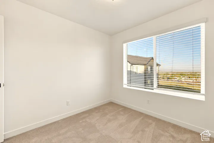 Neutral-toned wall-to-wall carpeting, expansive window with horizontal blinds, and textured neutral wall finish