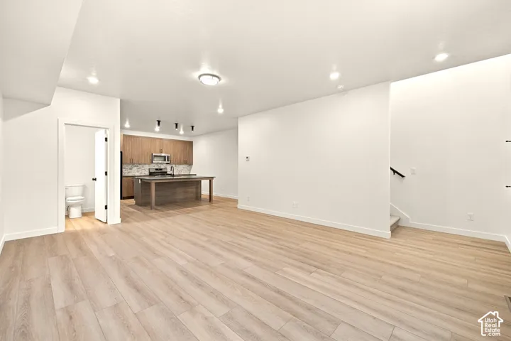 Open-concept interior featuring light wood-finish flooring, recessed lighting, a center kitchen island, and flat-panel wood cabinetry