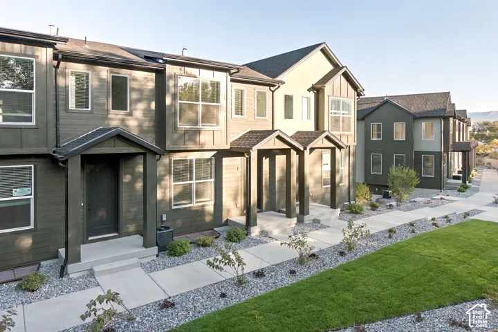 Multi-unit exterior featuring dark-toned horizontal siding, board and batten detailing, gabled entry overhangs, and concrete walkways