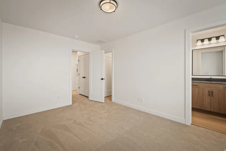 Neutral tone carpet flooring, white walls, and a contemporary ceiling light fixture