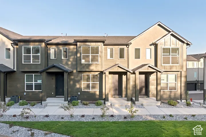 Multi-unit exterior featuring dark horizontal siding, vertical board-and-batten accents, gabled entryway covers, and concrete walkways