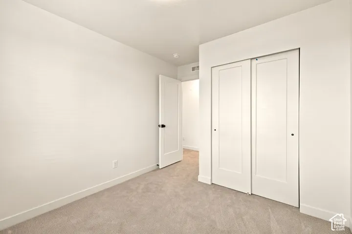 Neutral wall-to-wall carpeting, crisp white interior finishes, solid-core panel interior door, and sliding closet doors with recessed hardware