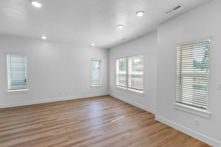 Recessed lighting, light wood-finish flooring, multiple windows with blinds, white walls, and white trim