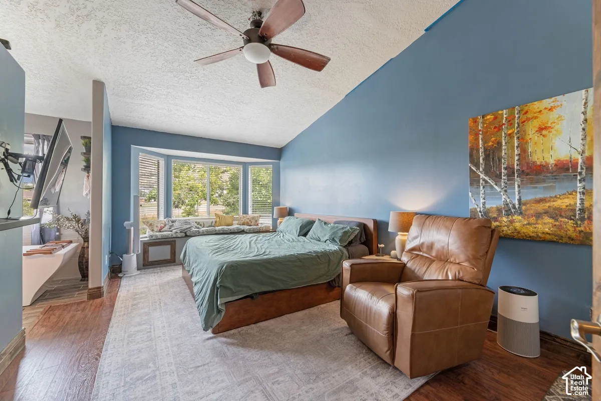 Vaulted ceiling, wood-finish flooring, bay window with integrated bench seating, and a ceiling fan with integrated lighting