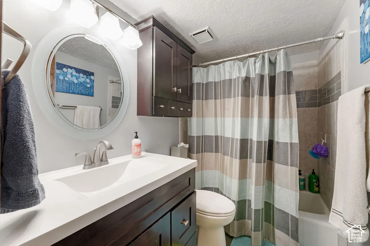 Vanity with integrated sink, dark wood-finish cabinetry, circular mirror, and overhead light fixture