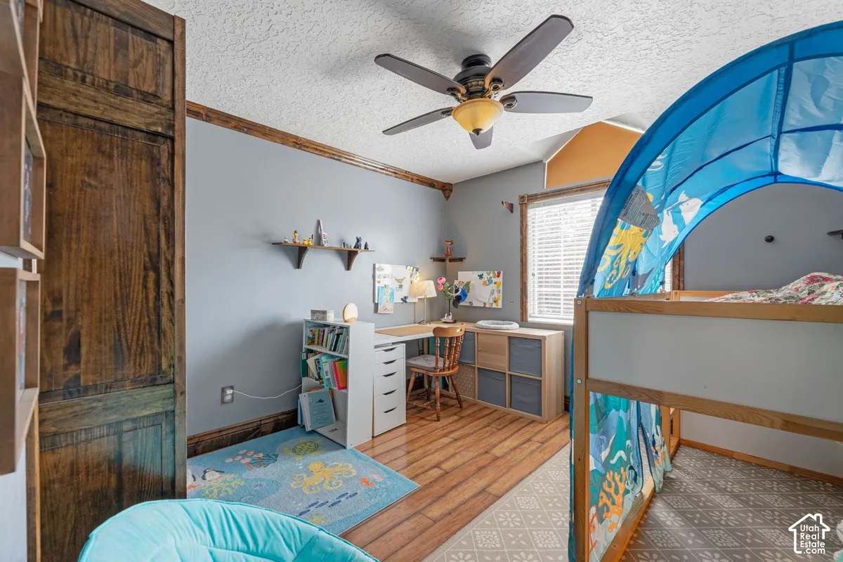 Wood-finish flooring, built-in shelving, ceiling fan, window with blinds, and decorative wood trim