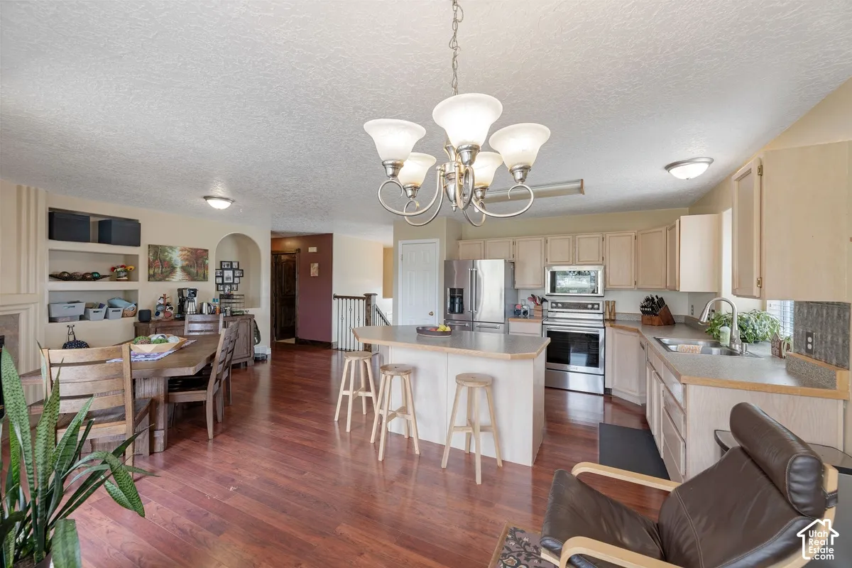 Kitchen with stainless steel appliances, wood-finish flooring, and a central island with bar seating