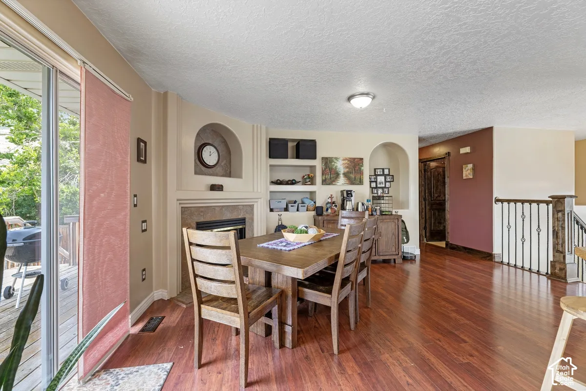 Wood-finish flooring, built-in shelving, fireplace with stone surround, arched wall niche, and sliding glass door