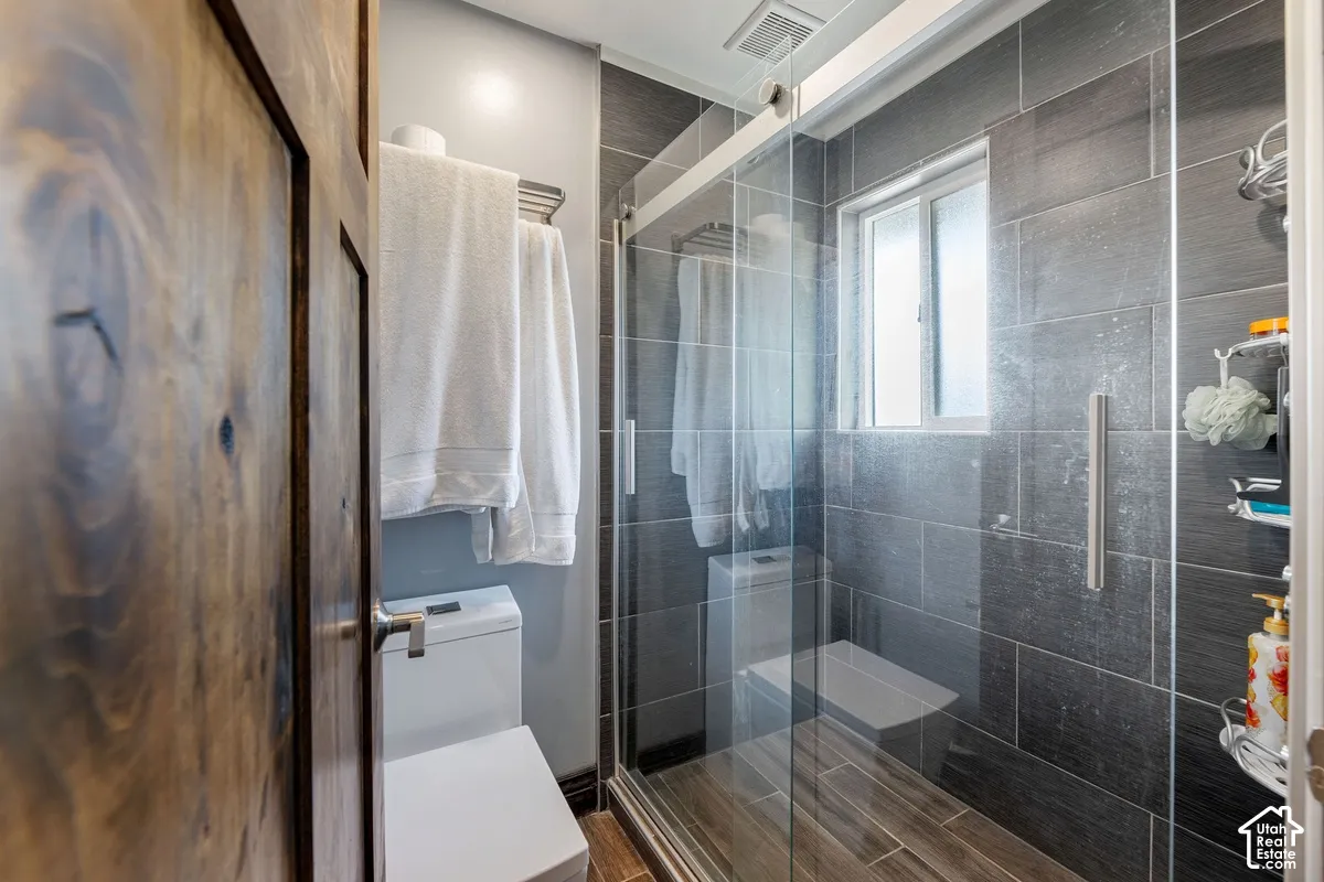 Enclosed shower with glass sliding door and dark rectangular tile surround