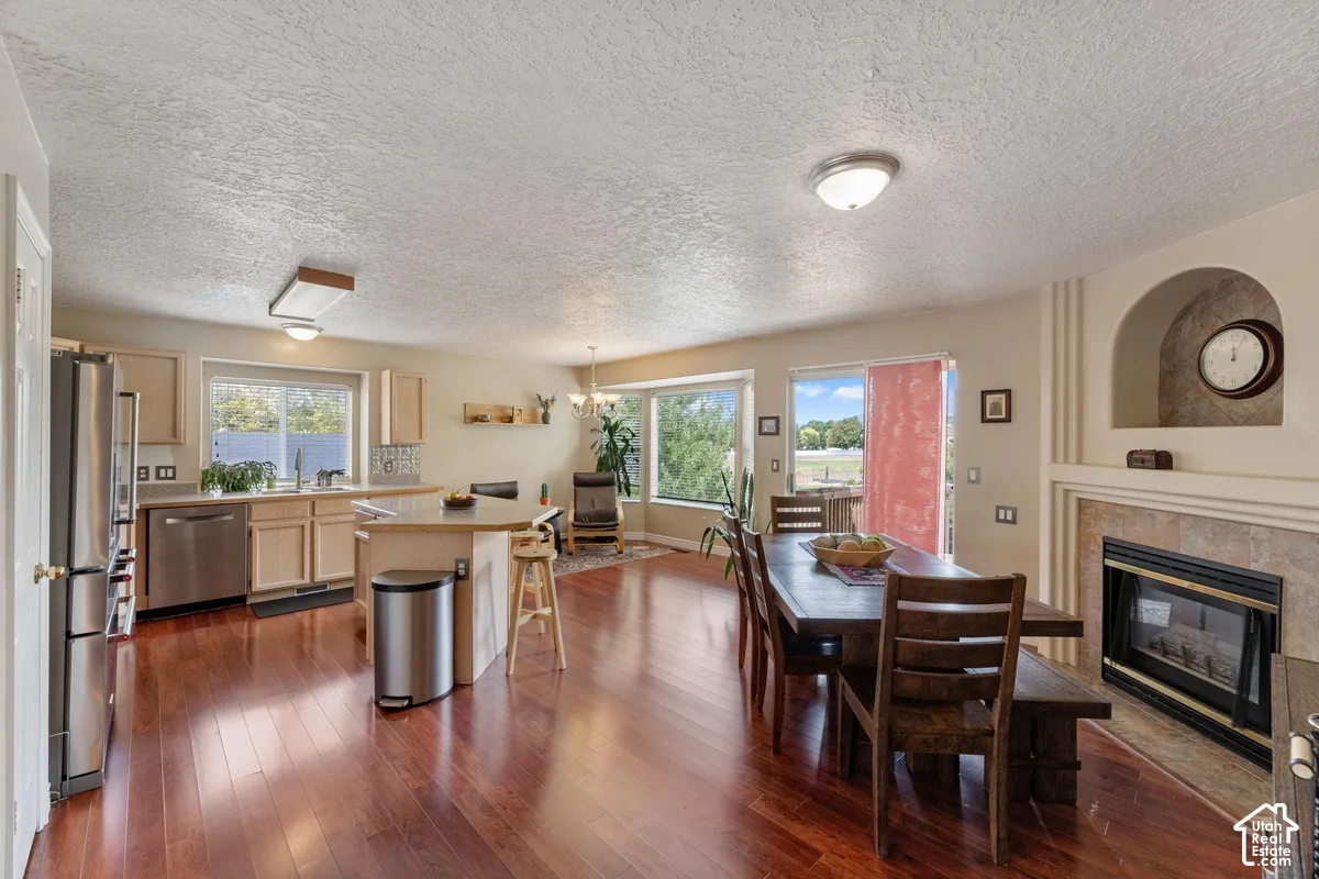 Hardwood-finish flooring throughout, stainless steel kitchen appliances, neutral cabinetry, a built-in fireplace with tile surround, and an arched niche feature