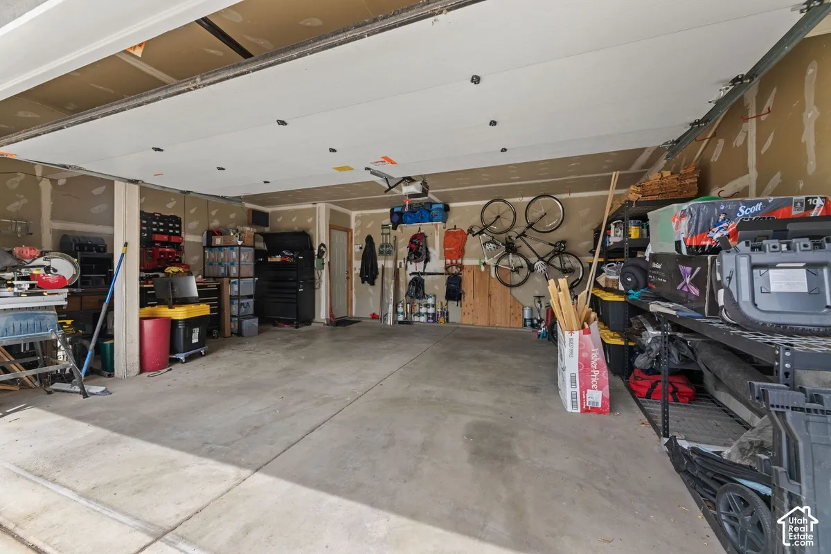 Concrete flooring garage with exposed ceiling joists and unfinished drywall