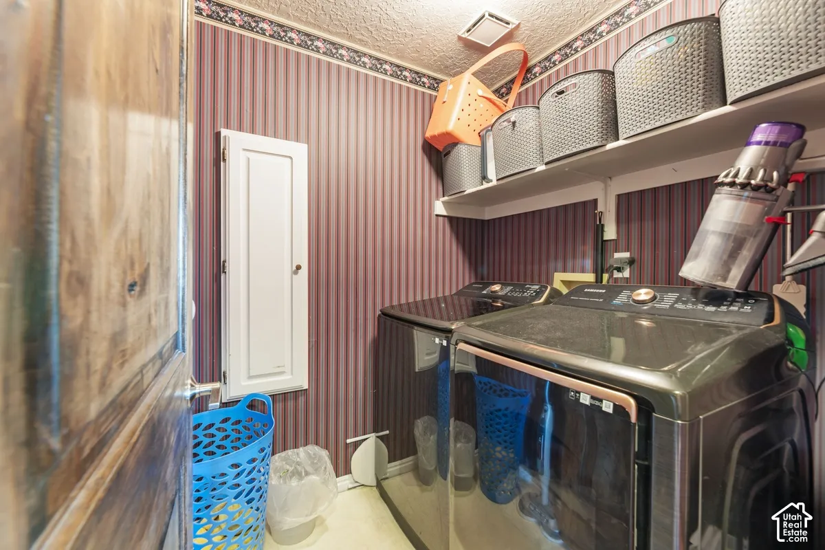 Laundry area featuring striped wallpaper, overhead shelving, and a built-in wall cabinet