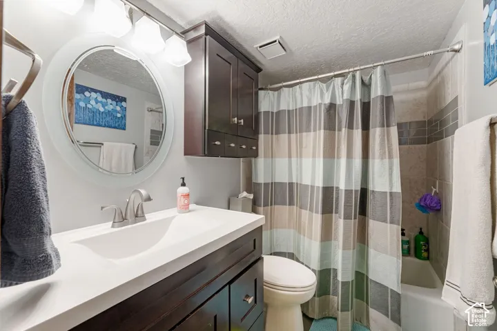 Vanity with integrated sink, dark wood-finish cabinetry, circular mirror, and overhead light fixture