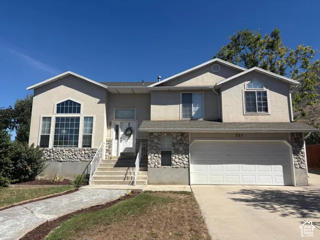 Exterior featuring a stucco finish, stone accents, multiple window styles, an attached two-car garage, and a concrete driveway