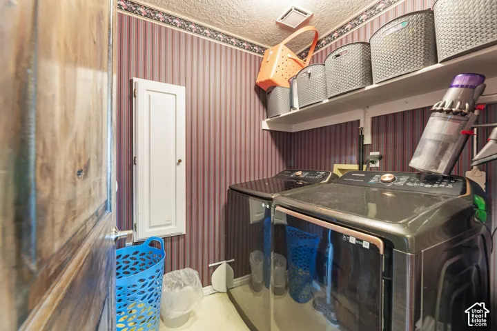 Laundry area featuring striped wallpaper, overhead shelving, and a built-in wall cabinet