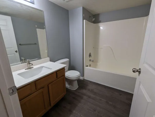 Wood-finish flooring, single vanity with light-toned countertop, integrated sink, and brushed nickel faucet