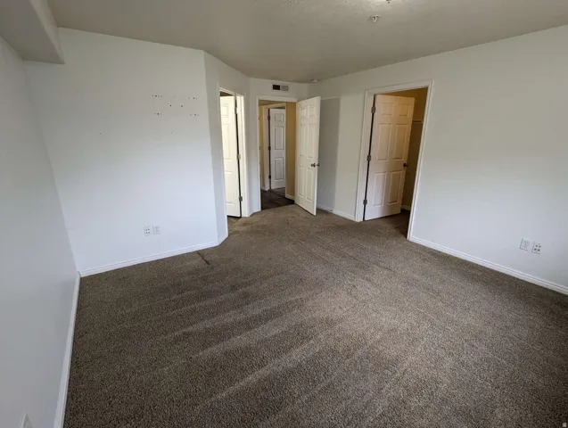 Carpeted flooring, white walls, multiple doorways, and white trim