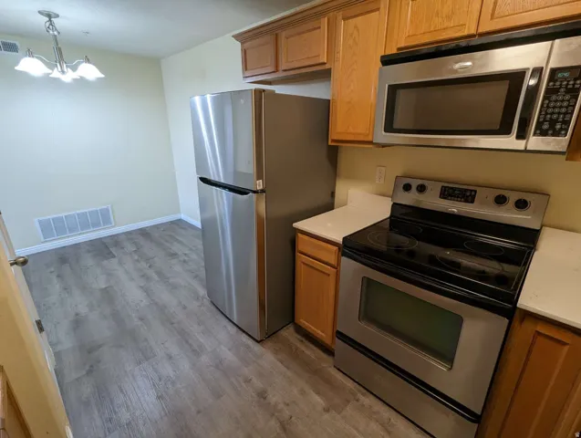 Stainless steel appliances, wood-finish flooring, light-toned cabinetry, and white countertops