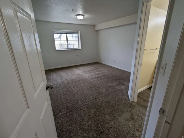 Wall-to-wall carpeting, window with horizontal blinds, built-in ceiling light fixture, closet with hanging rod, wood-finish flooring in closet