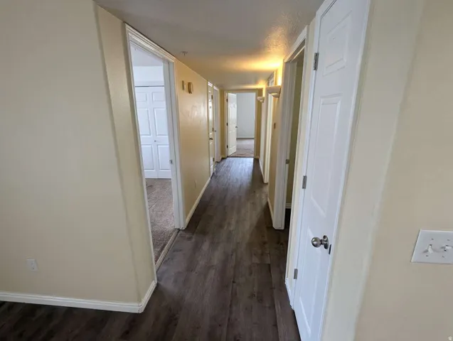 Hallway featuring wood-finish flooring, light-toned walls, white trim, and paneled doors