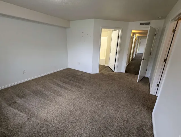 Carpeted room with white walls, baseboard trim, and multiple doorways