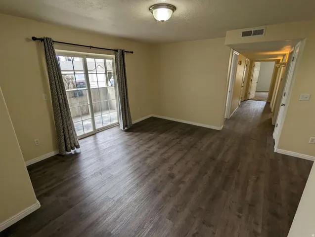 Wood-finish flooring throughout, with a sliding glass door leading to an outdoor patio
