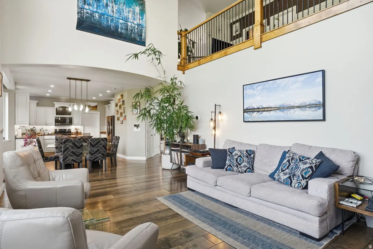 Vaulted ceiling with an open loft, wood-finish flooring, recessed lighting, arched entryway, and a contemporary kitchen with white cabinetry