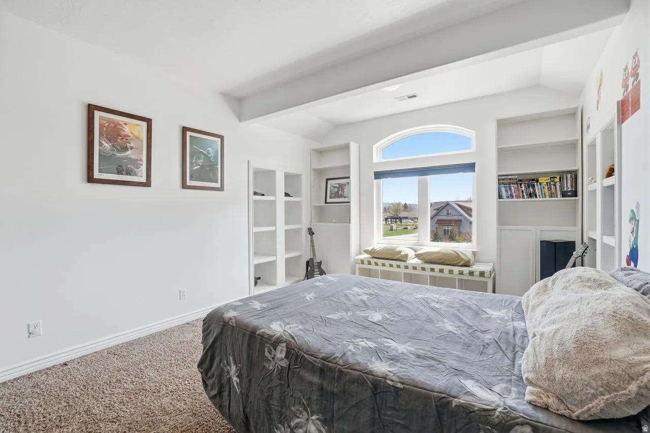 Arched window with a window seat, built-in shelving, high ceilings, and carpet flooring