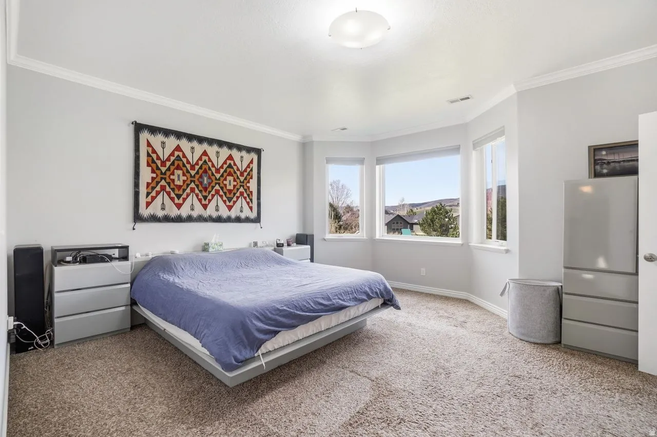 Recessed lighting, crown molding, bay window, light gray wall paint, and neutral-toned carpeting