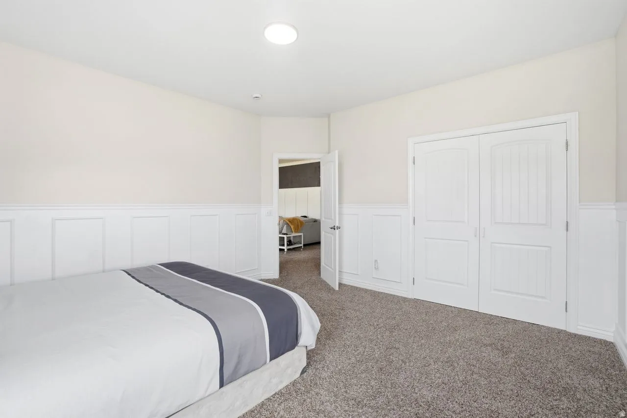 Recessed ceiling lighting, wainscoting wall detail, neutral color palette, carpeted flooring, and white double doors
