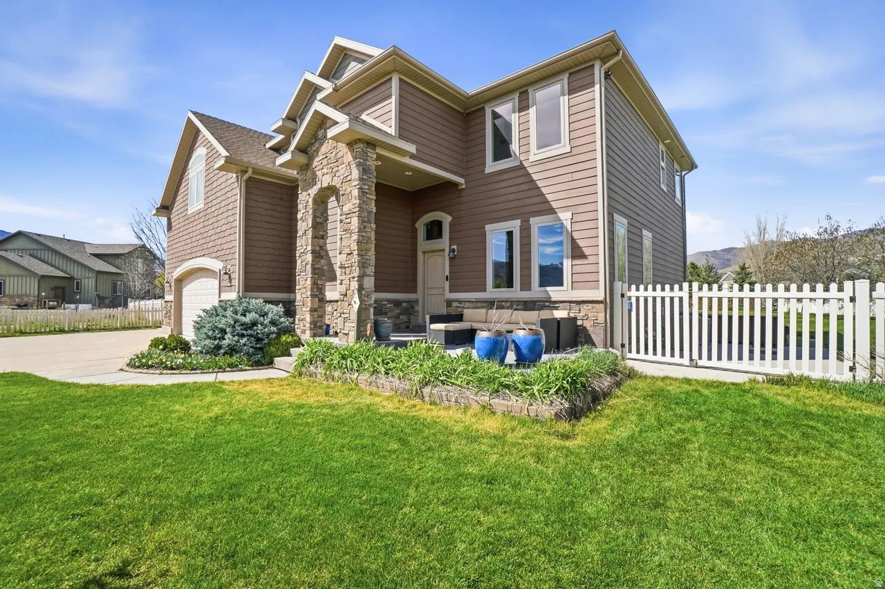 Two-story residence featuring composite siding, stone facade accents, an arched entryway, and an attached two-car garage
