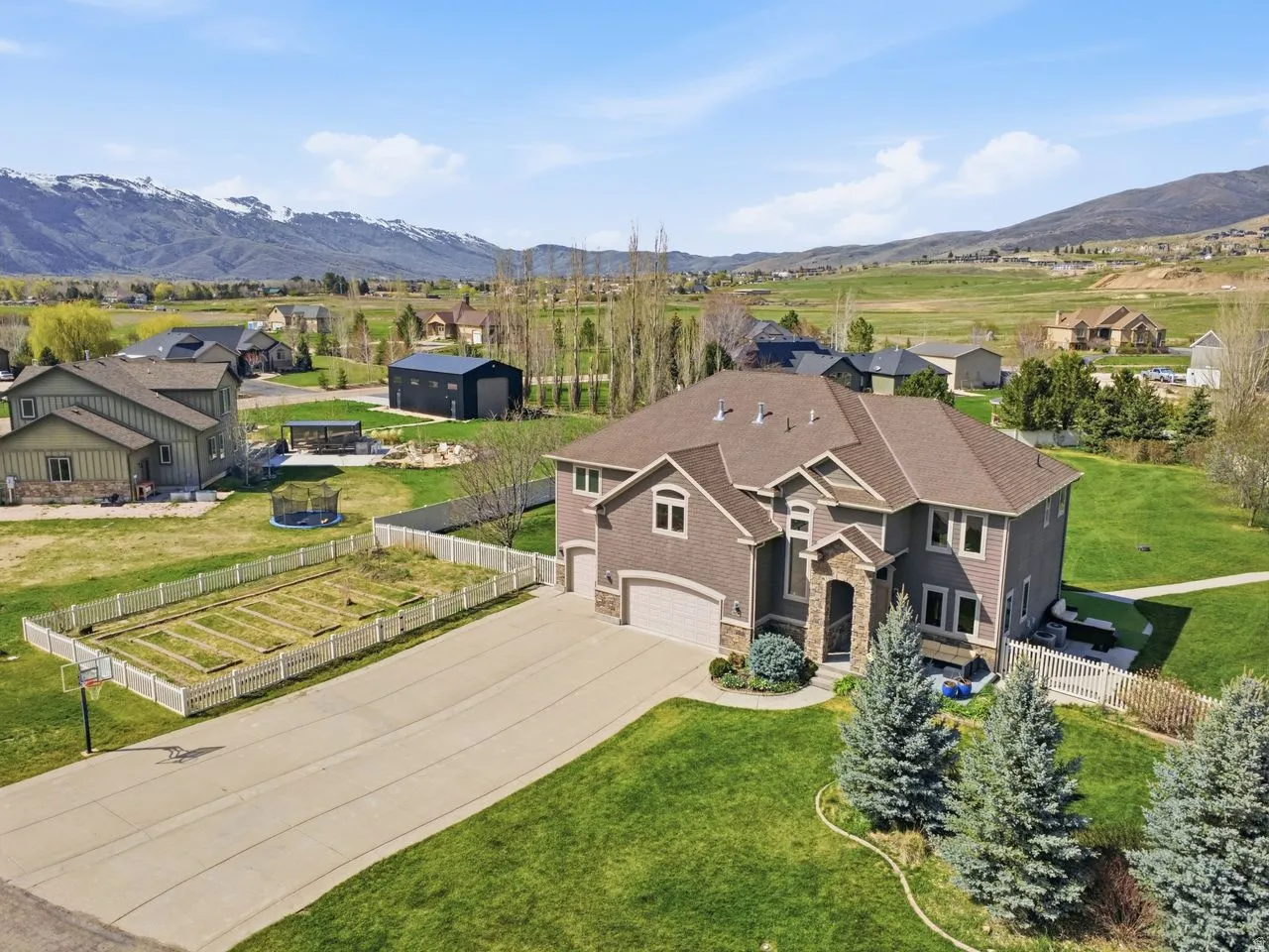 Expansive residential property featuring a multi-level structure with a stone facade, a multi-car garage, and a paved driveway