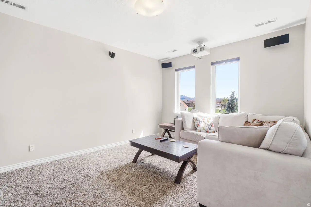 Recessed ceiling projector, two windows, wall-mounted speakers, recessed ceiling lighting, and carpeted flooring