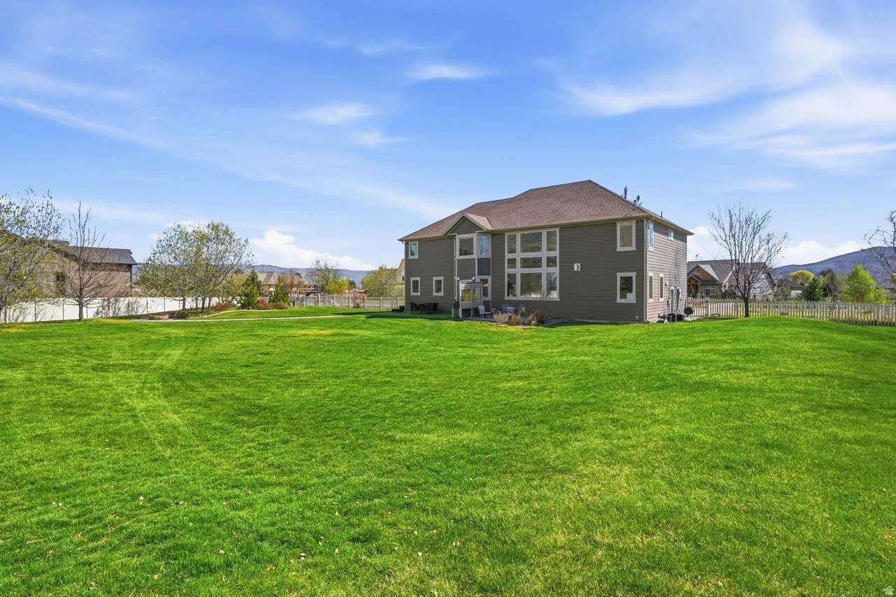 Expansive green lawn with mature trees and a fenced perimeter